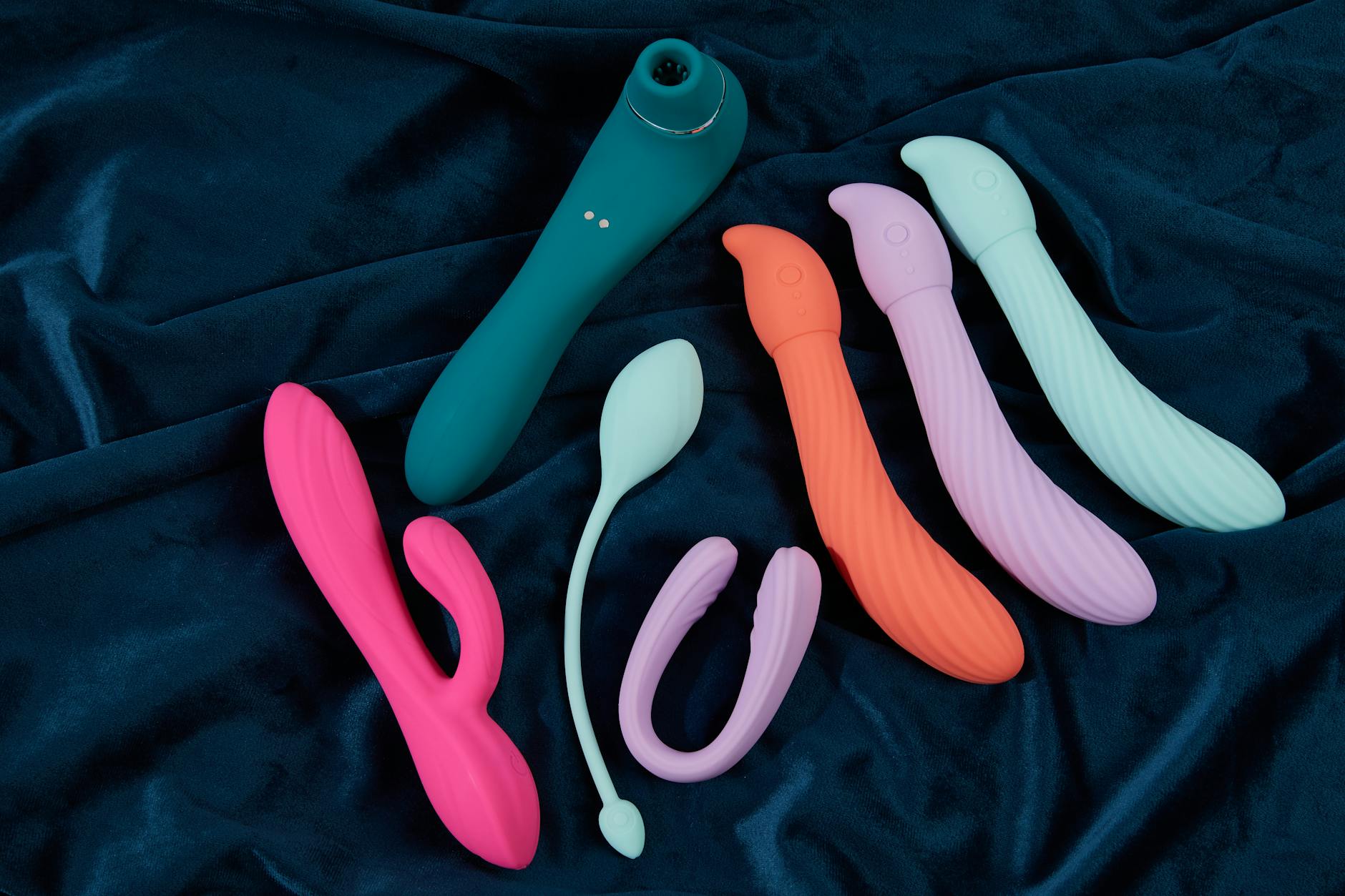 Woman thoughtfully holding two silicone vibrators, representing first-time nervous exploration