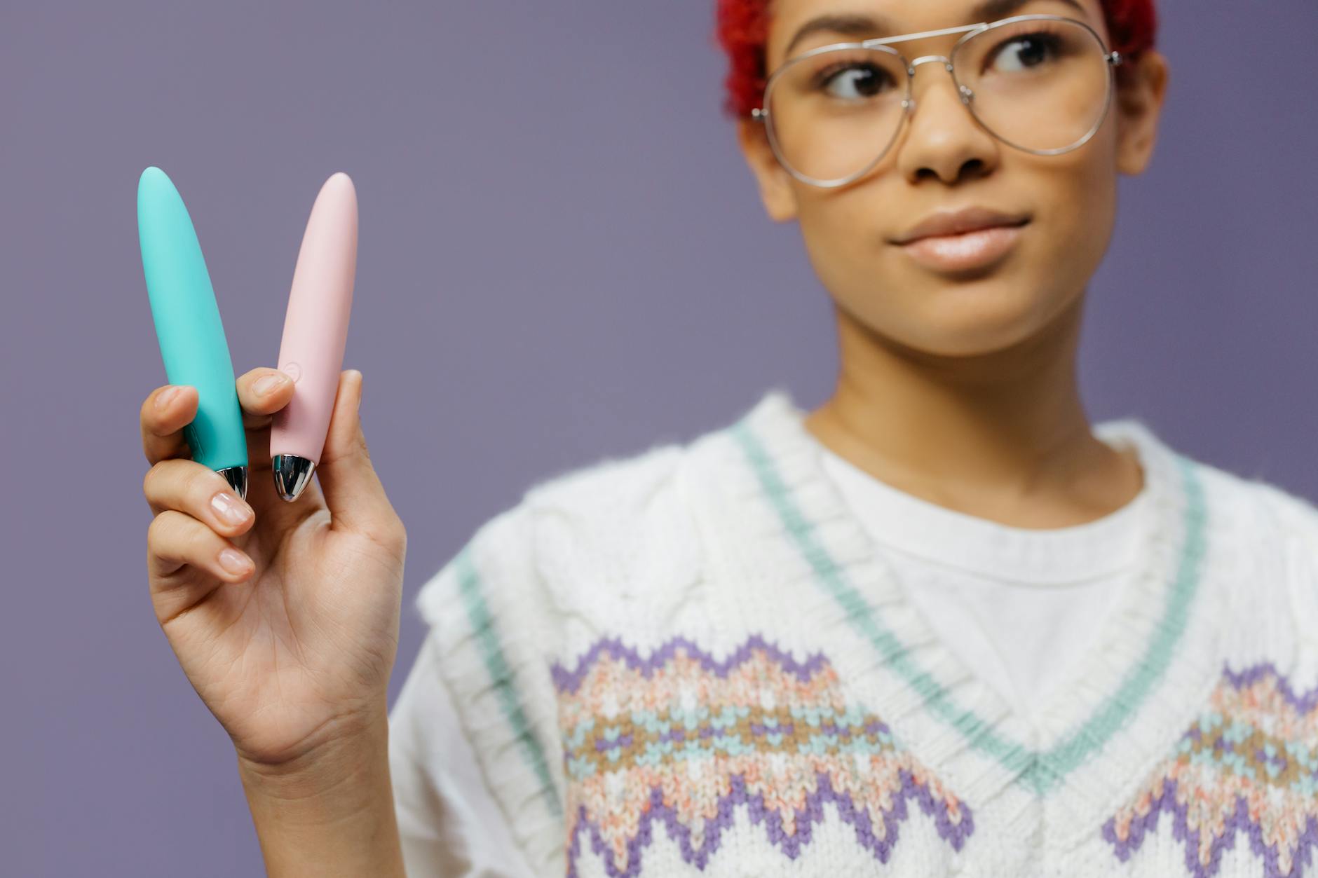 Blue clitoral vibrator held in hand against purple background