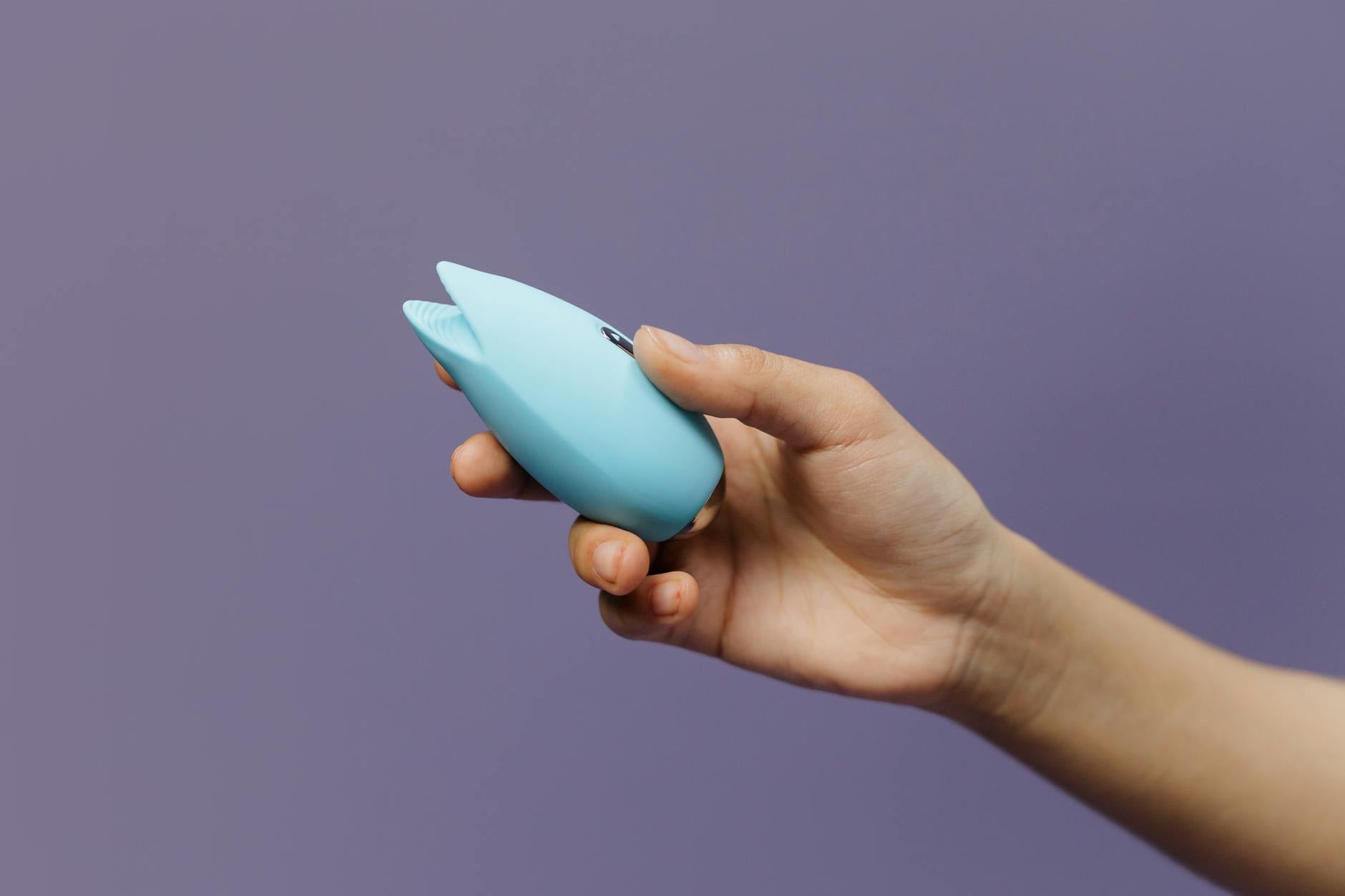 A lemon clitoral vibrator held in hand against a purple background, emphasizing personal choice and self-pleasure.