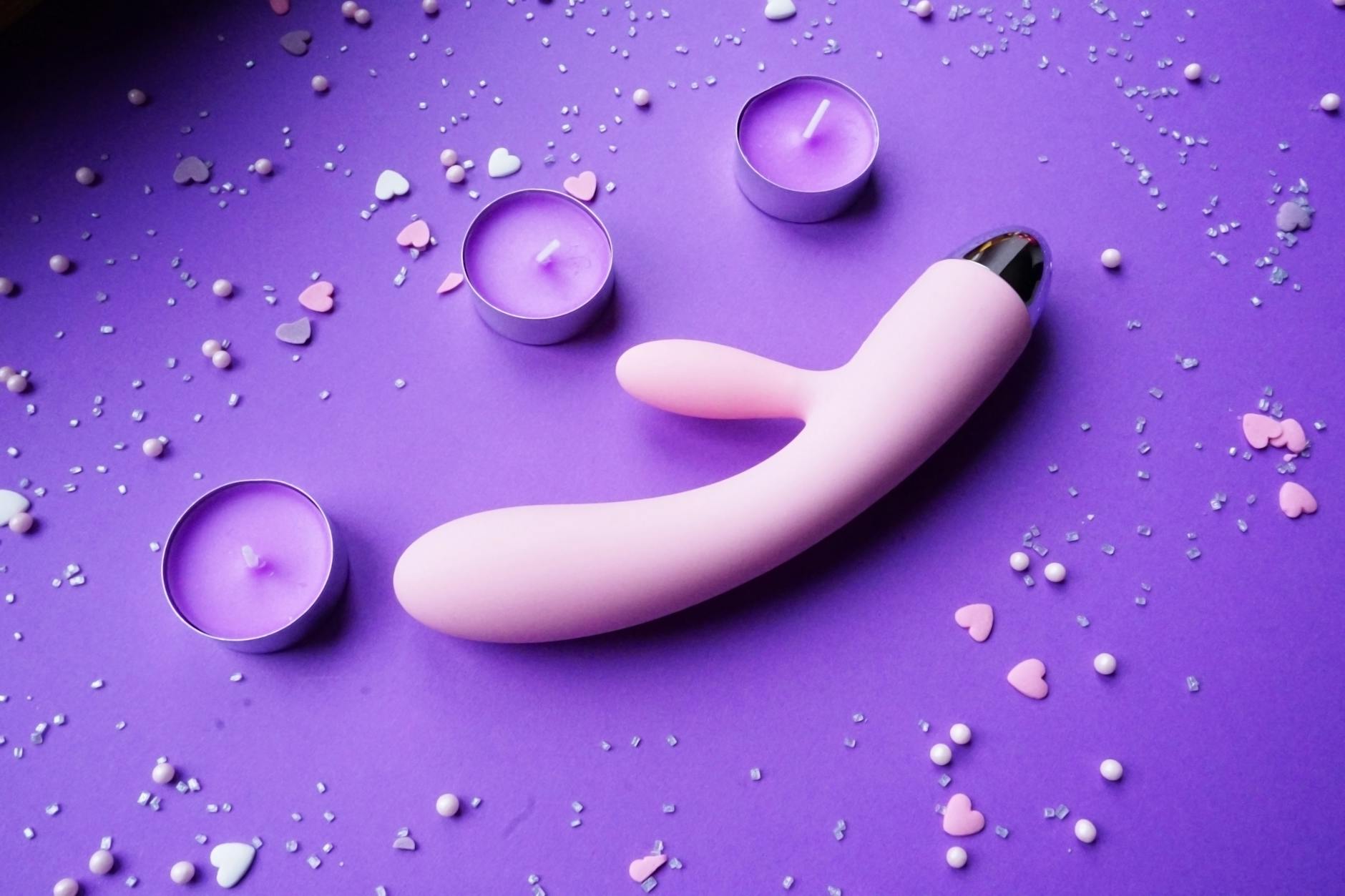 Woman holding blue and pink clitoral vibrators in contemplation